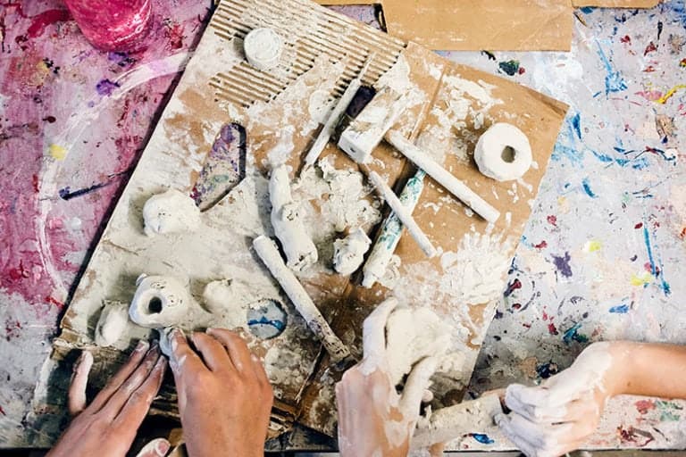 Clay sculpting activity at Eden Village Camp, children creating art with modeling clay, hands shaping clay sculptures, engaging outdoor arts and crafts for kids in a camp environment.