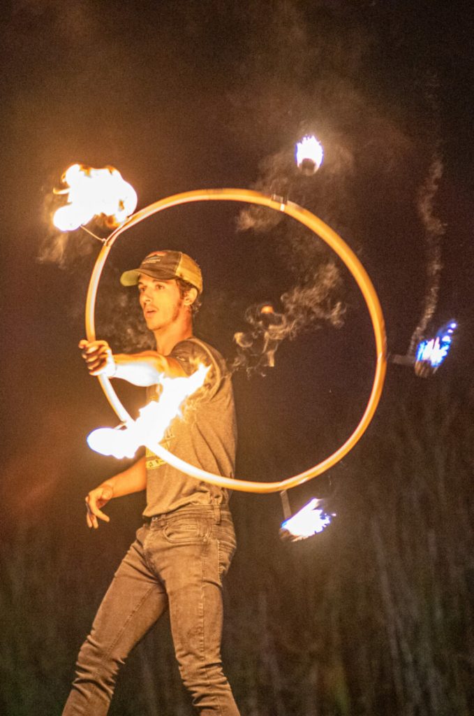 A person performing with a flaming hoop at night.