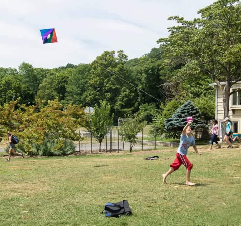 Colorful diamond-shaped kite flying in the sky at Eden Village Camp during outdoor activities.