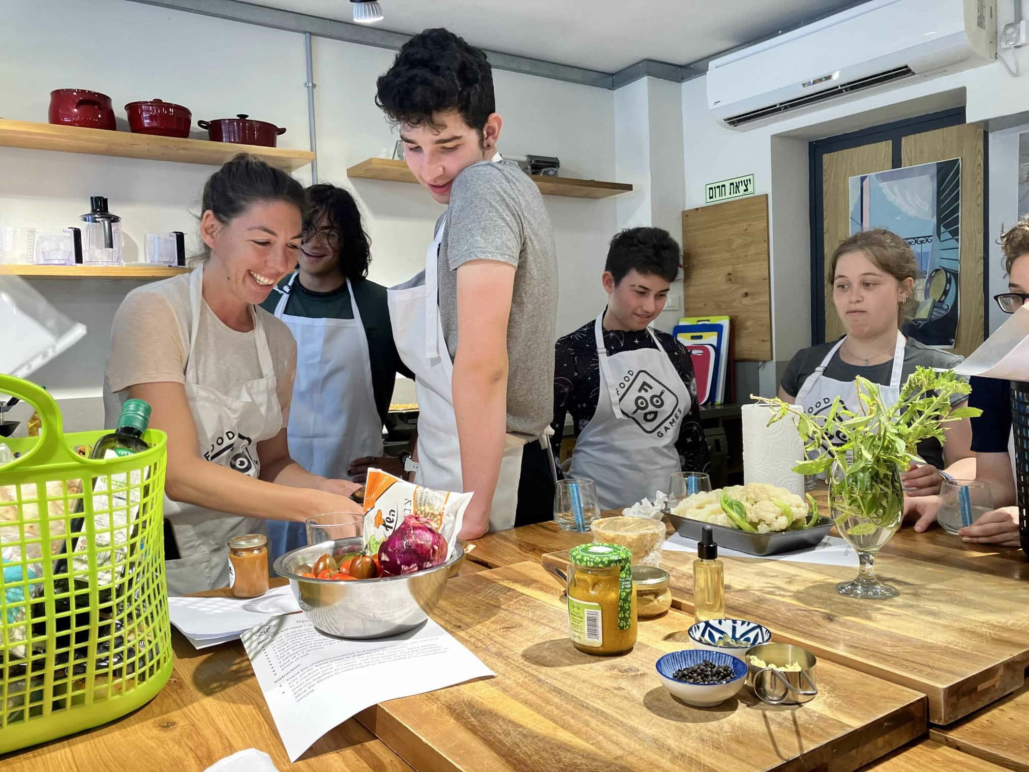 A group of individuals engaged in a cooking class, smiling and preparing ingredients.