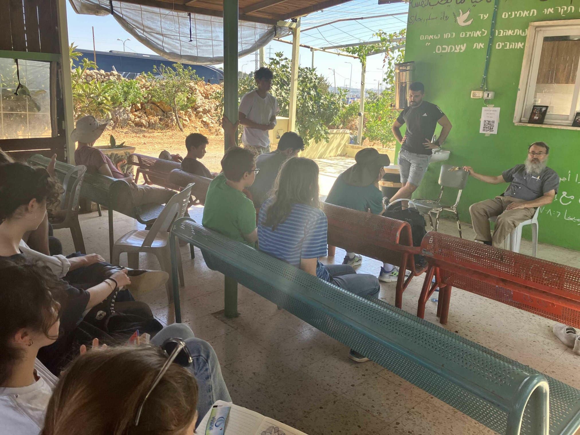 A group of individuals seated in a colorful outdoor space, engaging with a speaker.