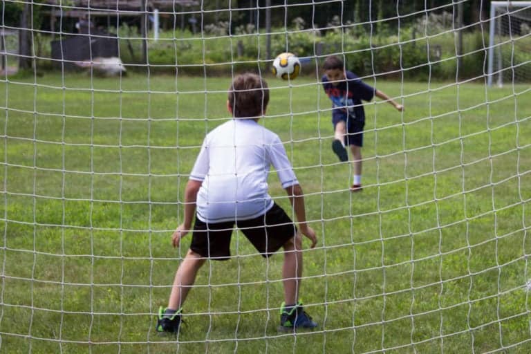 Kids playing soccer at Eden Village Camp, summer camp activities, kids outdoor sports, family-friendly camp, outdoor adventure activities at Eden Village Camp.