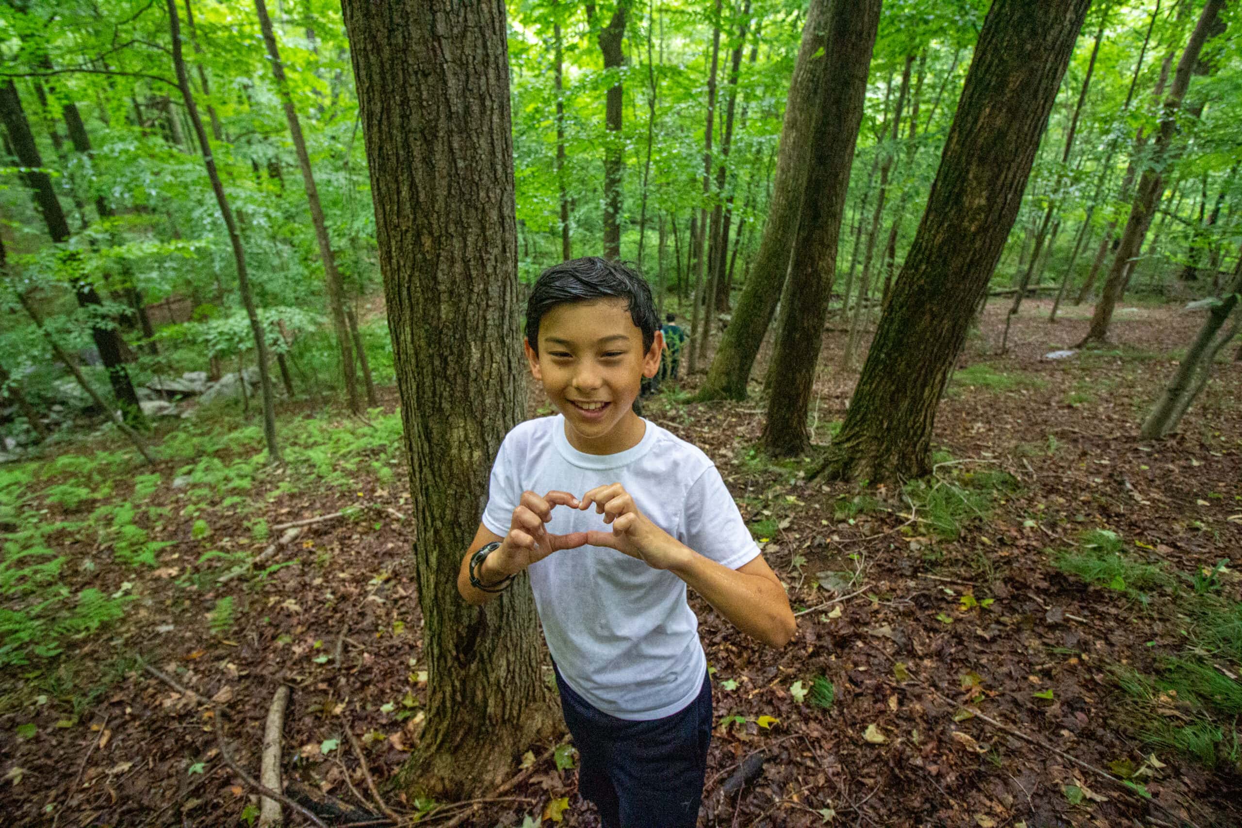 camper in forest making heart symbol with hands