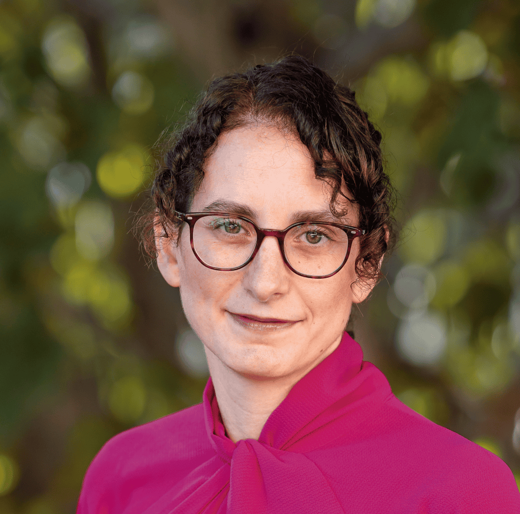 Eden Village Camp outdoor educational environment with a woman wearing glasses and a pink top, emphasizing eco-friendly summer camp experiences and nature-based learning.