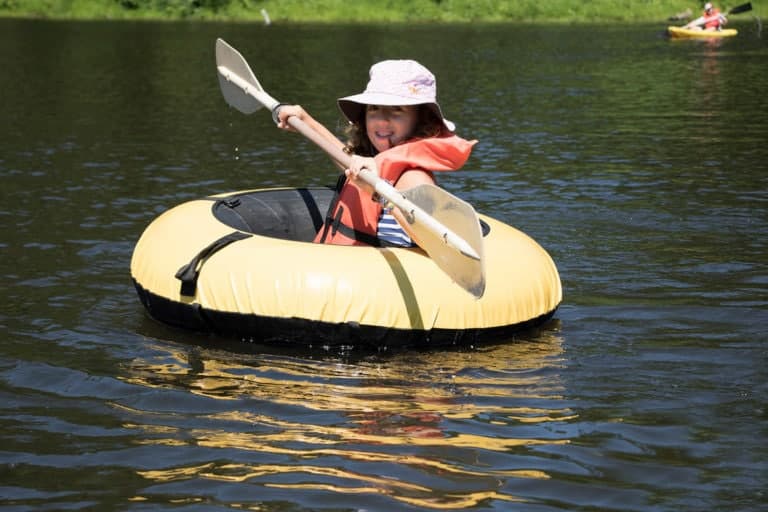 Kayaking at Eden Village Camp, children enjoying outdoor water activities, scenic lake environment, summer camp adventure, eco-friendly camping experience, youth outdoor recreation, nature exploration.