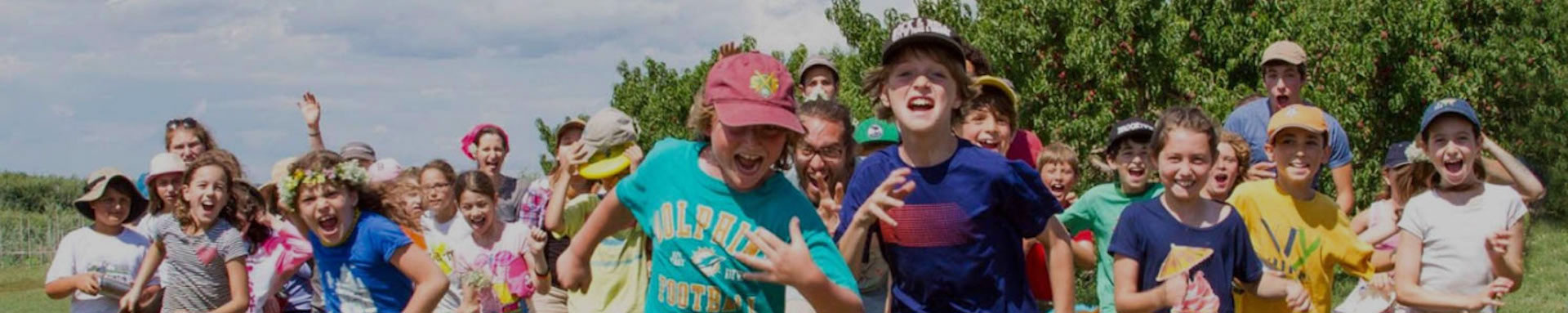 A group of children joyfully running in a green outdoor setting.