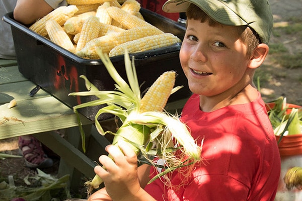 redefine-camp-2 camper posing with husked corn