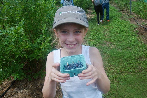 redefine-camp-3 camper holding organically grown blueberries