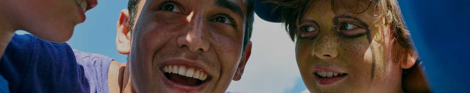 A group of smiling individuals enjoying a sunny outdoor event.