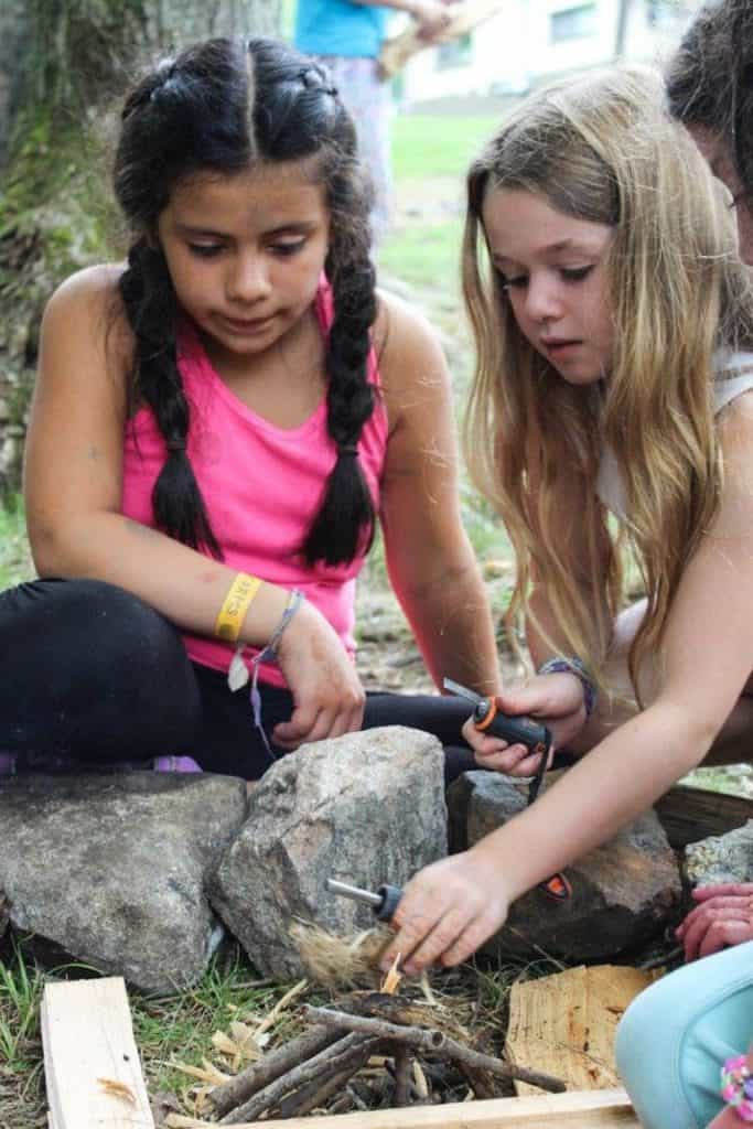 Children camping firemaking activities at Eden Village Camp, outdoor educational activities for kids, nature-based summer camp for children, eco-friendly youth camping experience, outdoor skills development for kids.