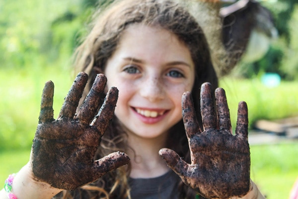 camper with mud on hands and smiling