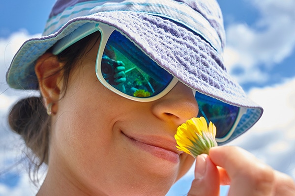 camper with hat and sunglasses smelling flower